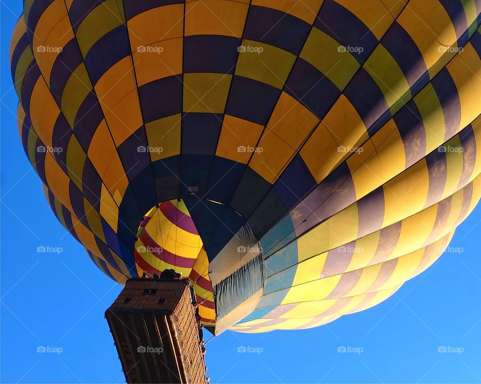 A yellow hot air balloon gently floating over the Napa Valley vineyards. 