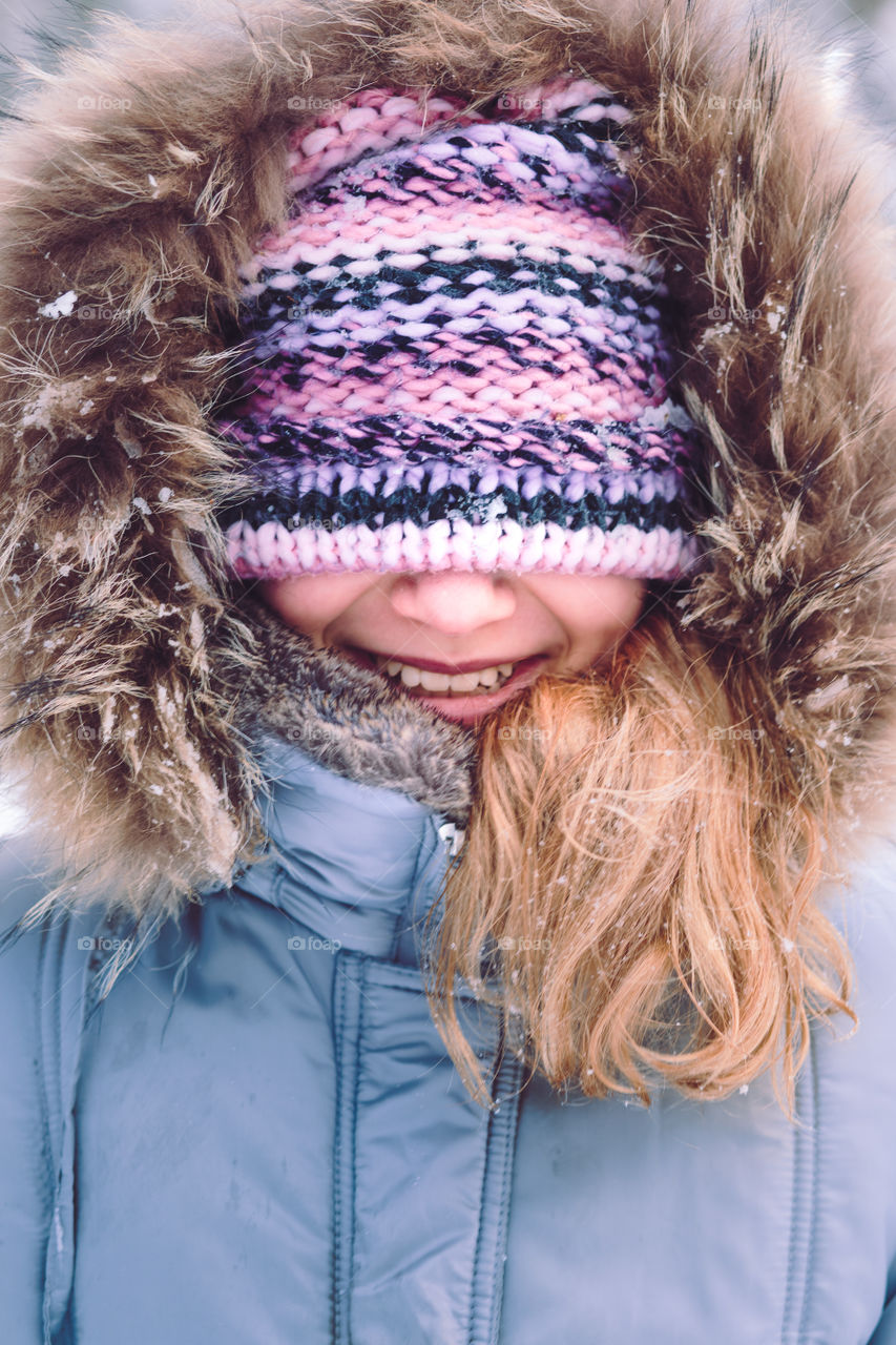 Portrait of girl with covered face with her hat outdoors in the wintertime