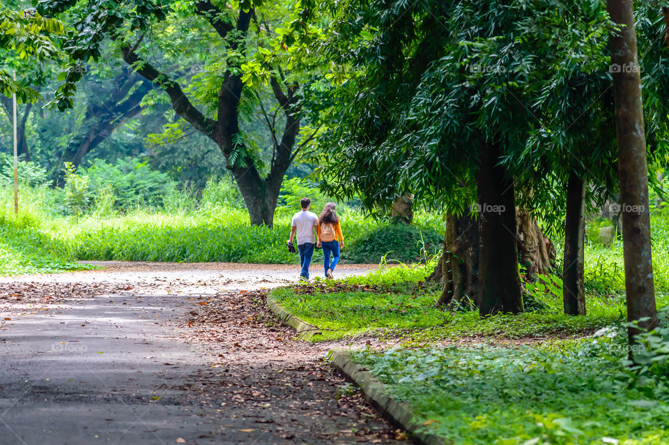 Portrait of two joyful young loving Couple walking in a green autumn park on a romantic summer day. Pre-wedding marriage engagement concept. Togetherness composition. Botanical garden, Kolkata, India