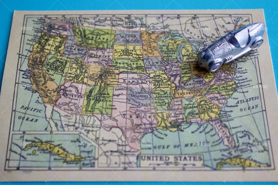 Miniature silver racer heading southwest on a miniature vintage map of the United States of America against a sky blue background