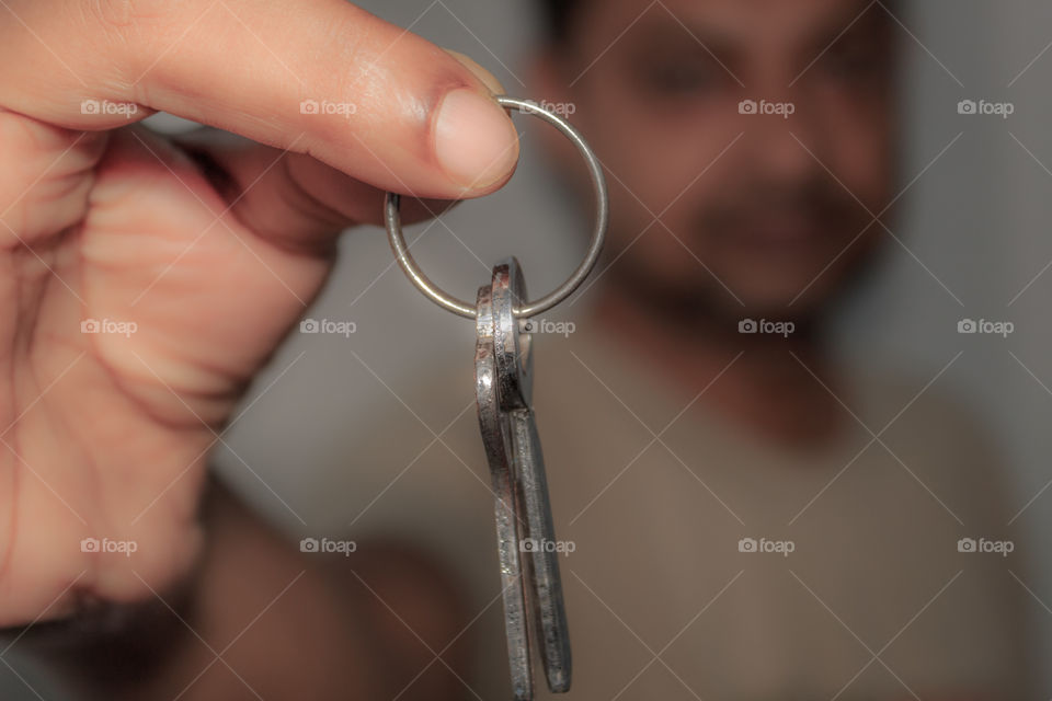Close up of real estate selling person holding a bunch of antique two iron metal keys attached on a ring, it on isolated white background. Selective focus with copy space. Safe secure business concept
