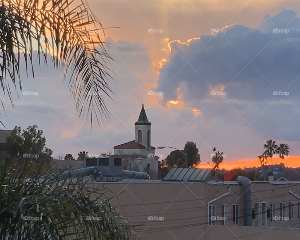 Church spire against a backdrop of clouds at sunset
