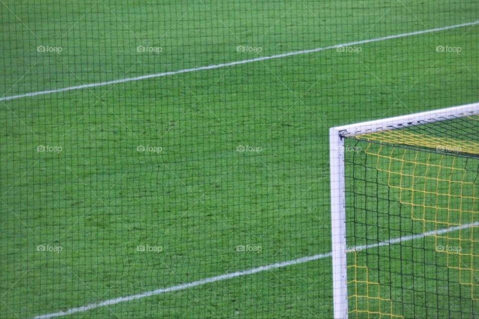 Close-up of a soccer goal on green grass with white lines