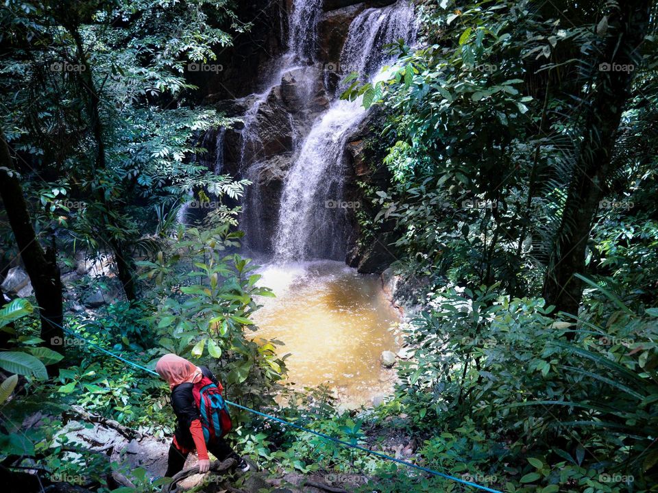 A girl hiking in the rainforest with a beautiful waterfall in the background