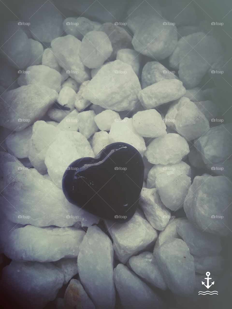Black Heart shaped rock Surrounded but other plain rocks. Everything is unique, even in rocks.