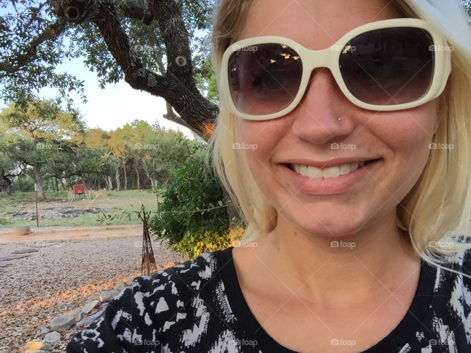 beautiful young blond woman wearing sunglasses while enjoying her time spent outdoors