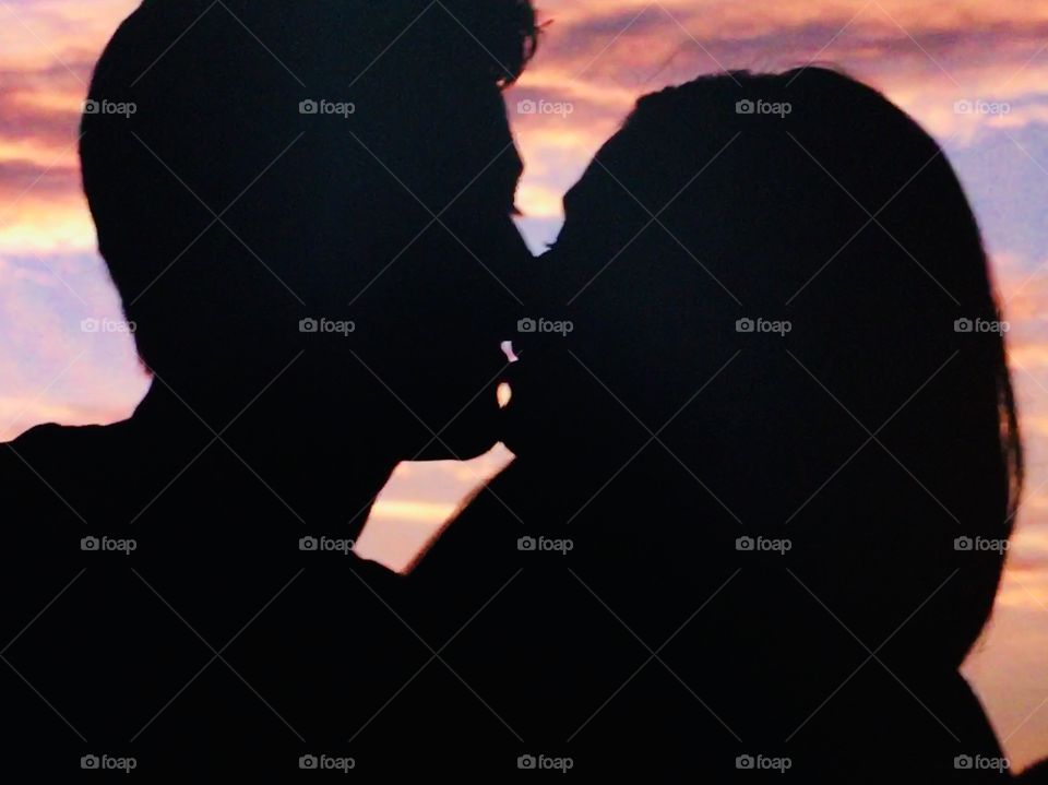 Silhouette kiss beautiful colorful sky behind 