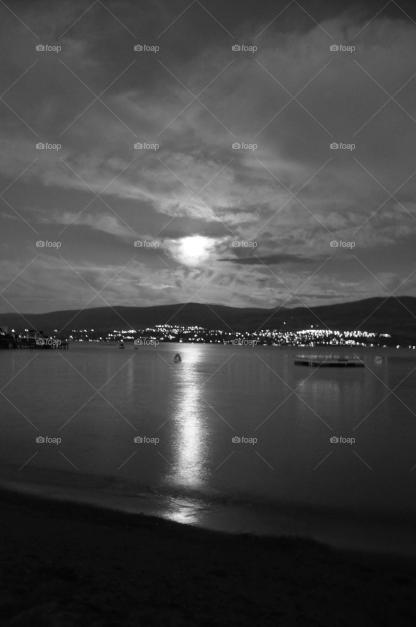 Moonlight reflections on the lake with city lights 