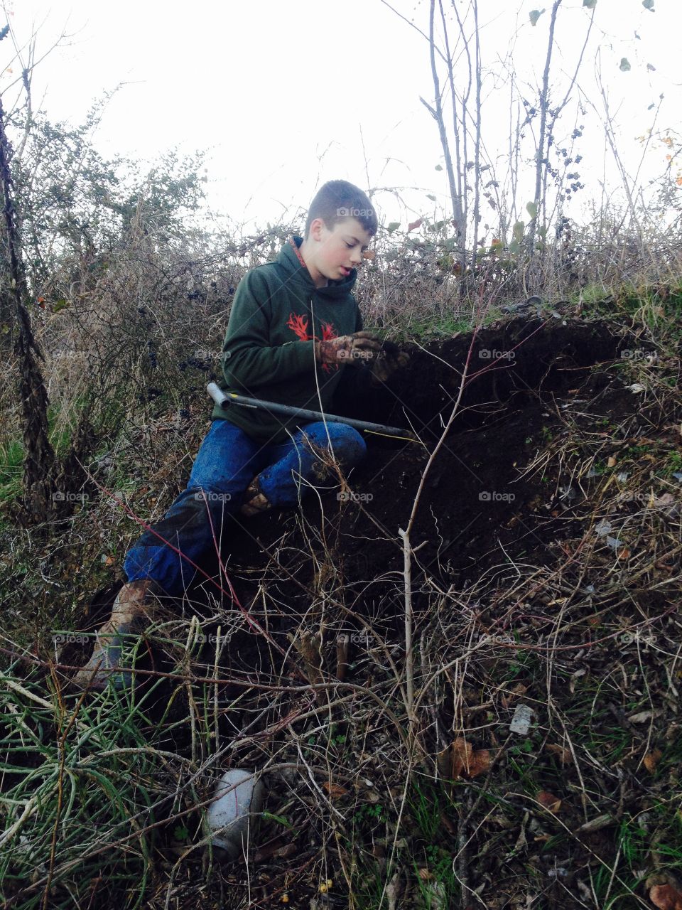 View of a boy sitting on soil holding object