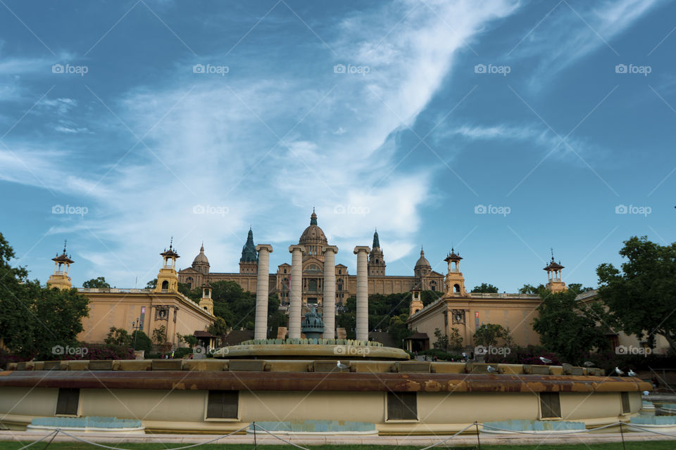 The magic fountain show in Barcelona. The square is full of columns, fountains and stairs, with a beautiful museum behind it. At night everything is framed by the show.