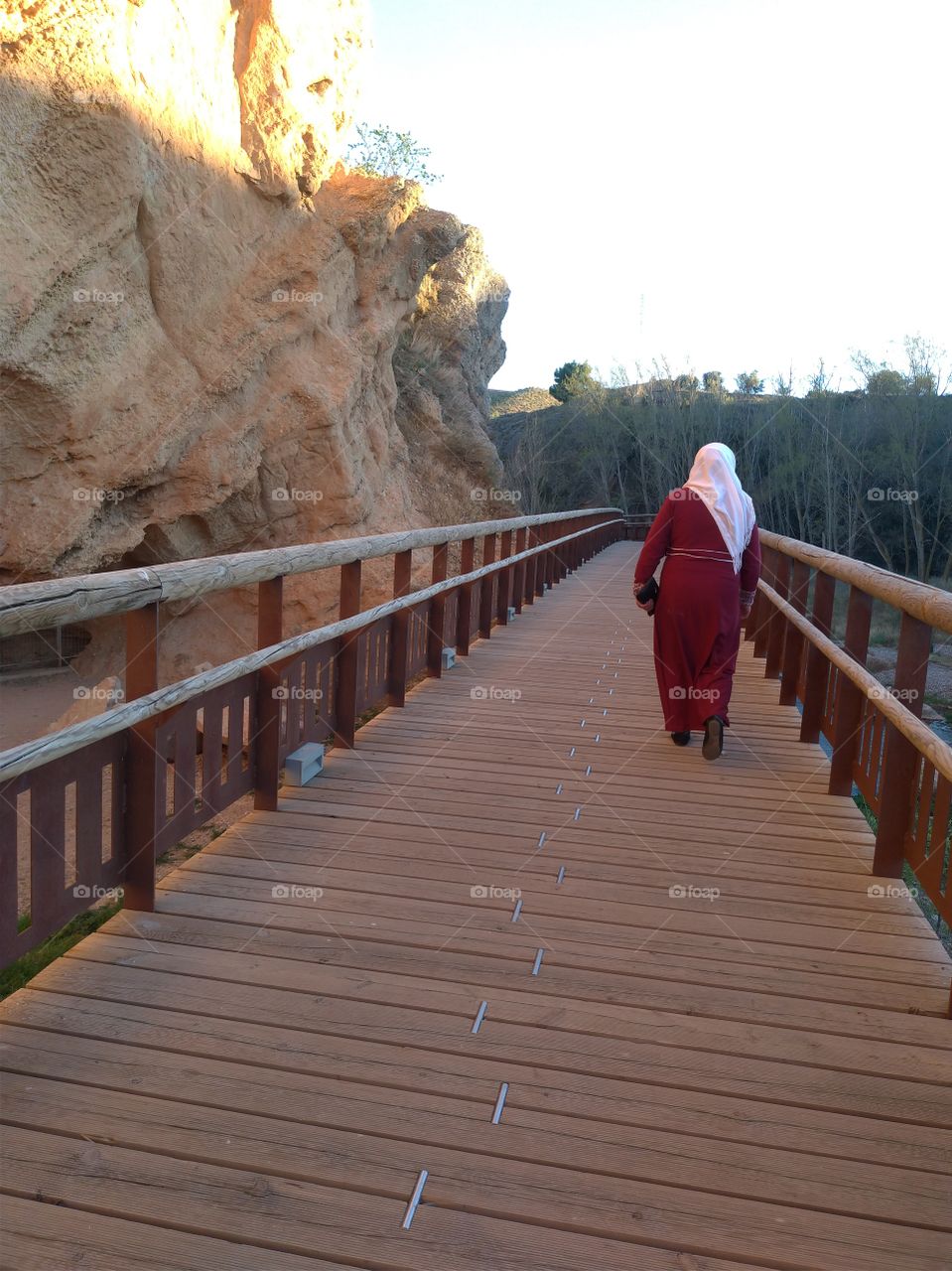 Una mujer musulmana caminando por un puente de madera