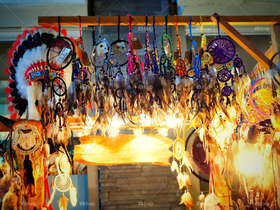 Dream catcher souvenirs hanging in shop with orange lights accent in the background.