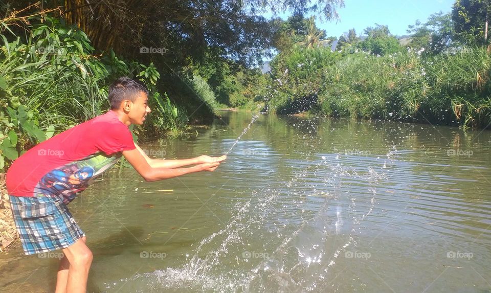 Chlild sprinkles the water in a river