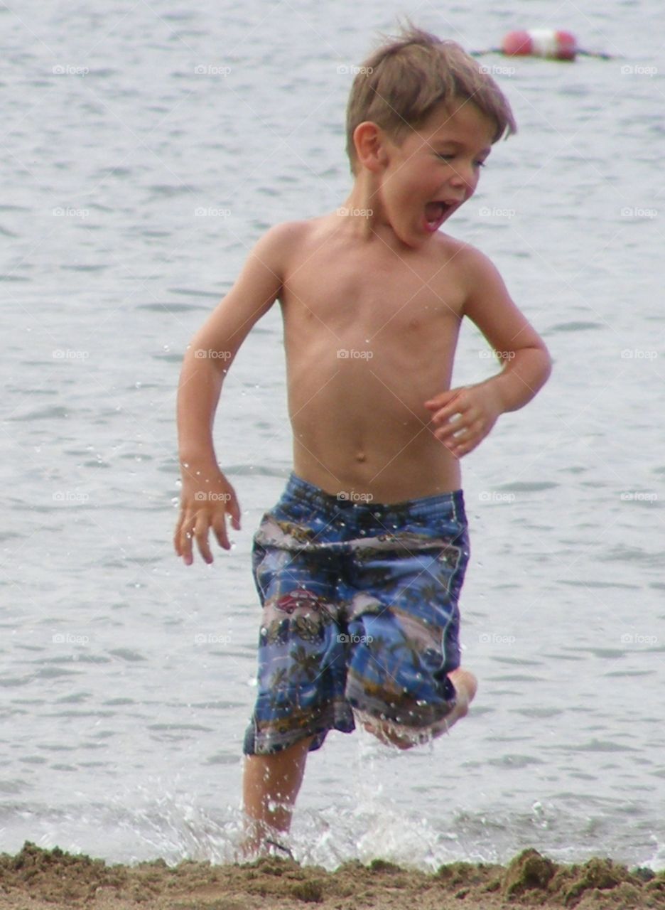 Young boy happily running through lake water