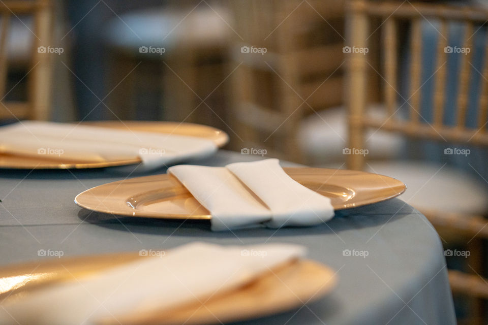 Gold plates and napkins on white linens tablecloth wedding reception table setting