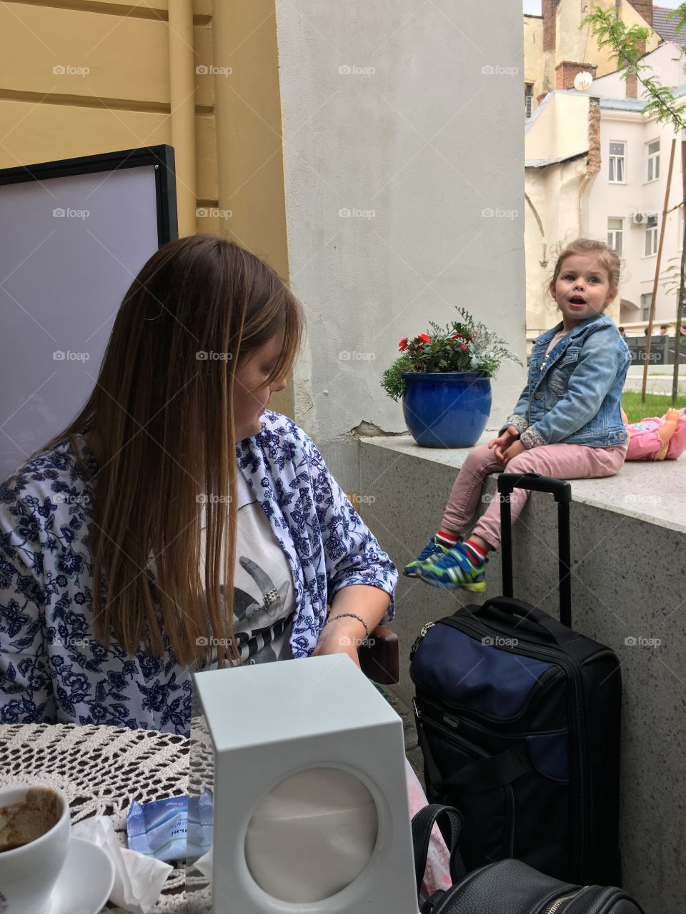 Cite girl is sitting happy with a suitcase before her vacation