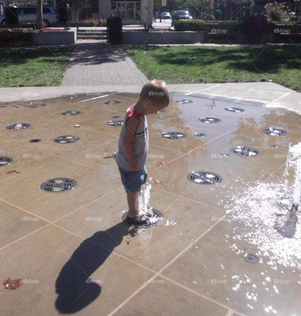 Boy playing in water fountain