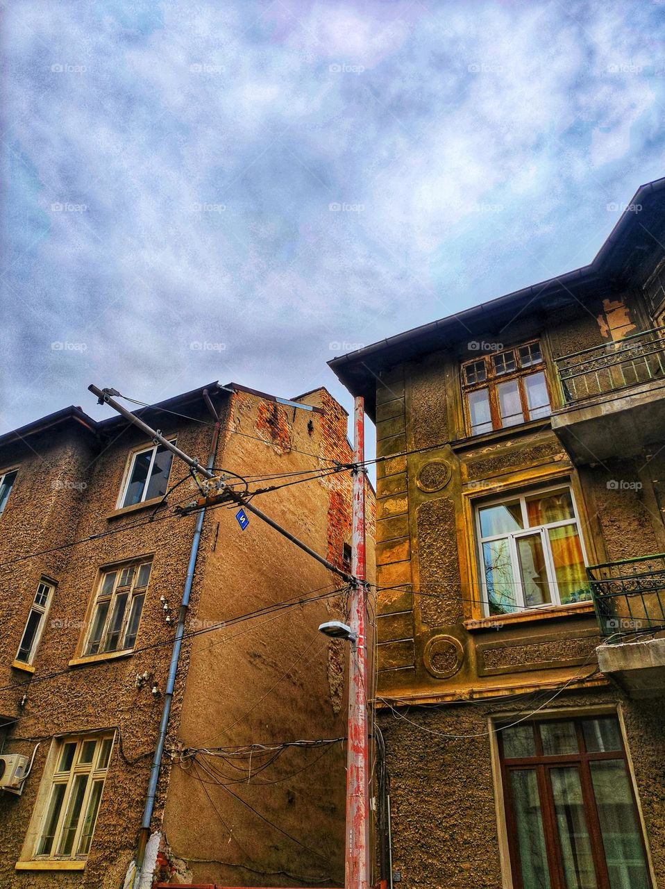 A picture of some old building's in the centre of the capital city of Bulgaria captured in the winter with a light pole and wires in front of them