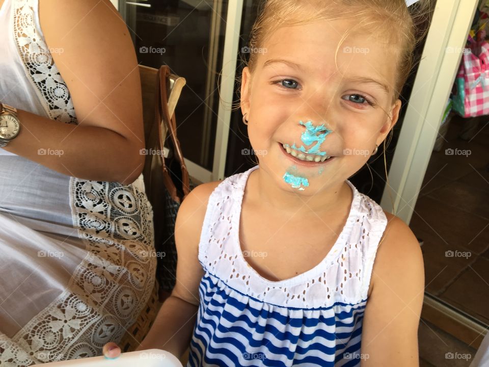 Funny little girl with cake on her face 
