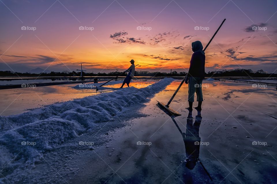 salt farmers during a sunset