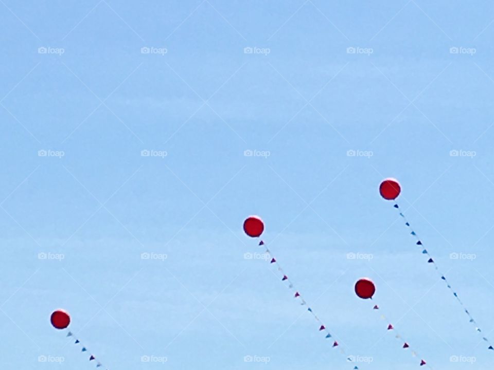 Red balloons floating in a blue sky