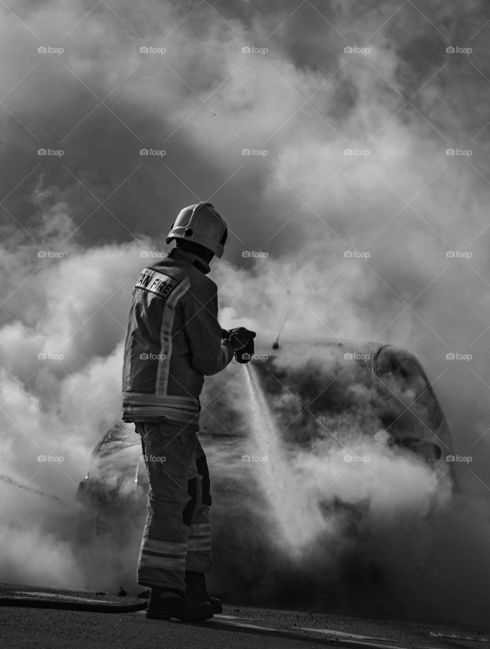 Firefighter tackling a car fire. 