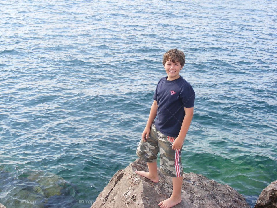 Boy standing on rocks next to Lake Michigan