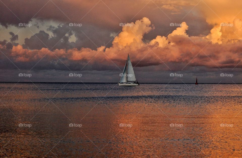 white sailboat at the dramatic cloudy sky during sunsey over the baltic sea in poland