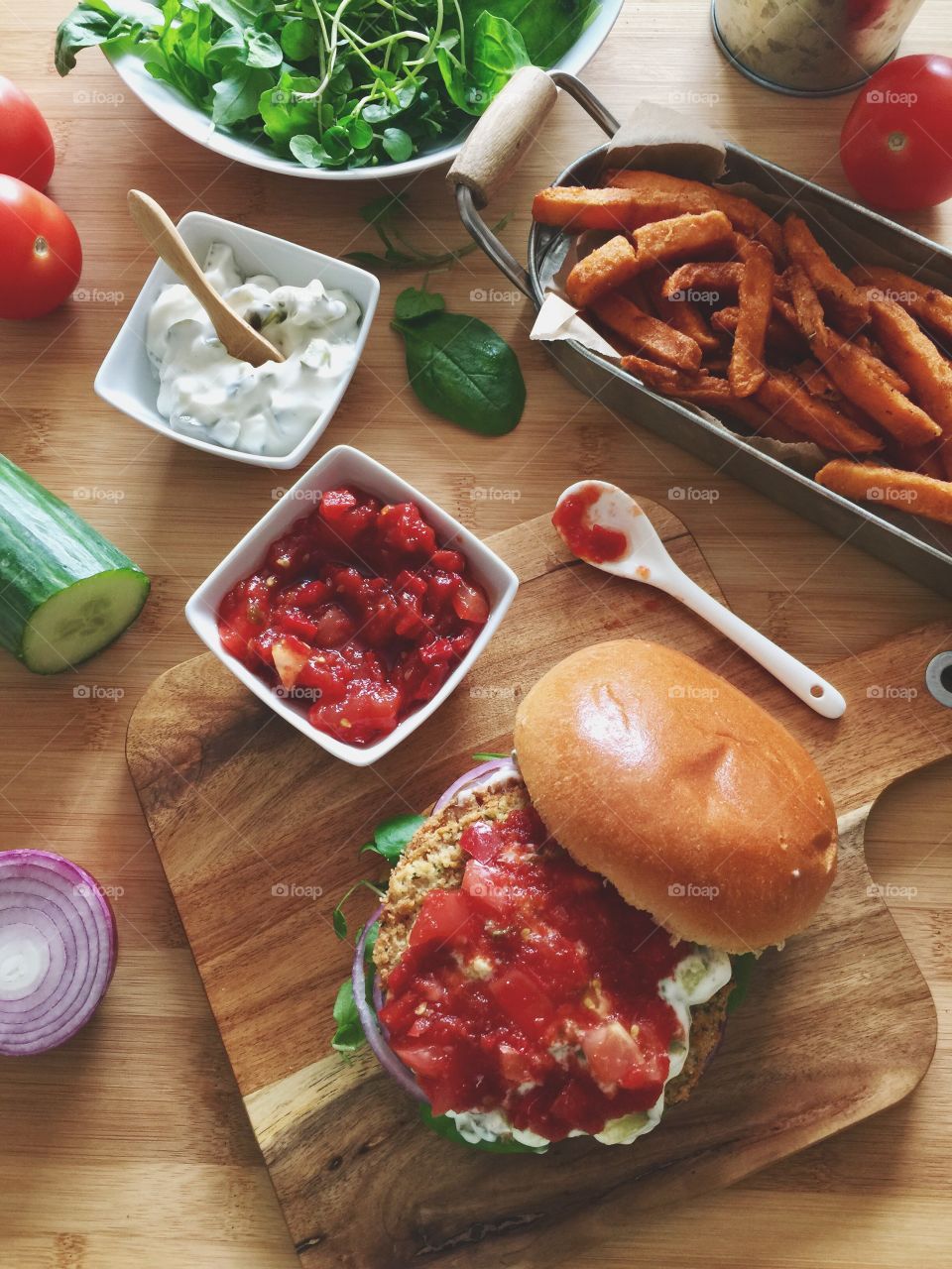 Spicy bean burger with tomato relish and sour cream served with sweet potato fries 