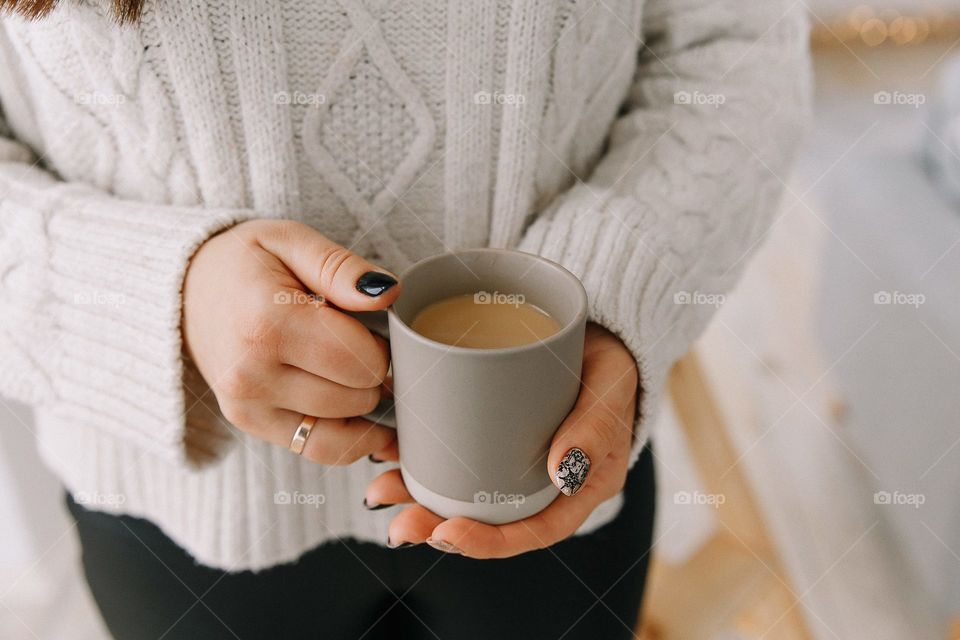 Cup of coffee with milk in female hands