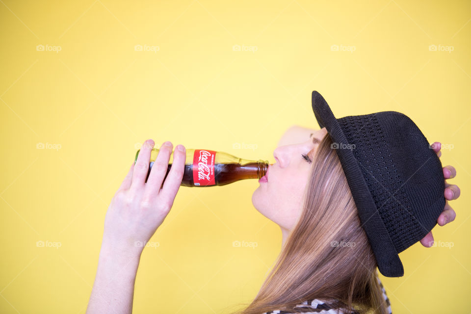 Portrait of a young woman drinking a bottle of Coca-cola