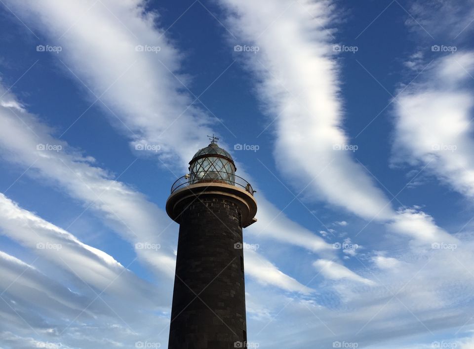 Top of lighthouse in front of clouds