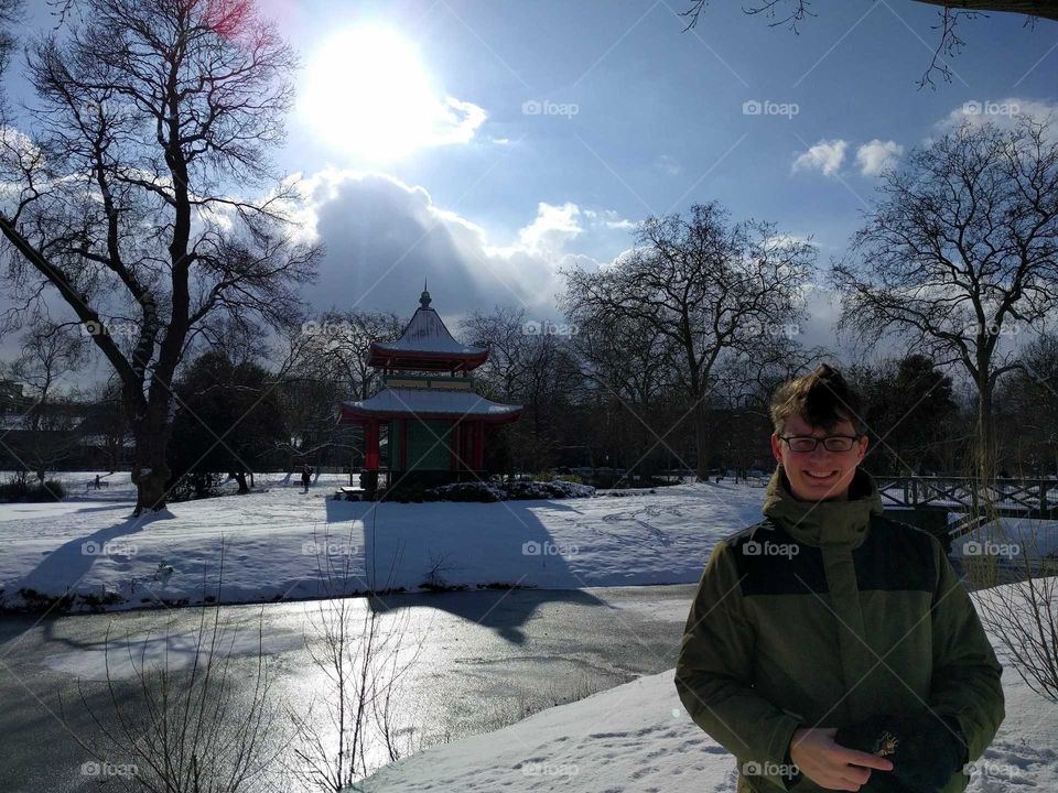 Man in the park in the snow with Chinese Pagoda