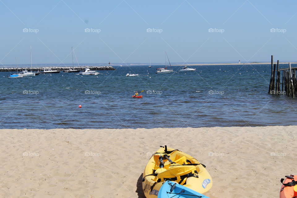 Yellow kayak on the beach near ocean with boats
