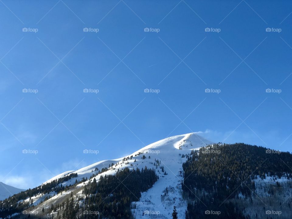 The grand snowy mountain peak with blowing snow.