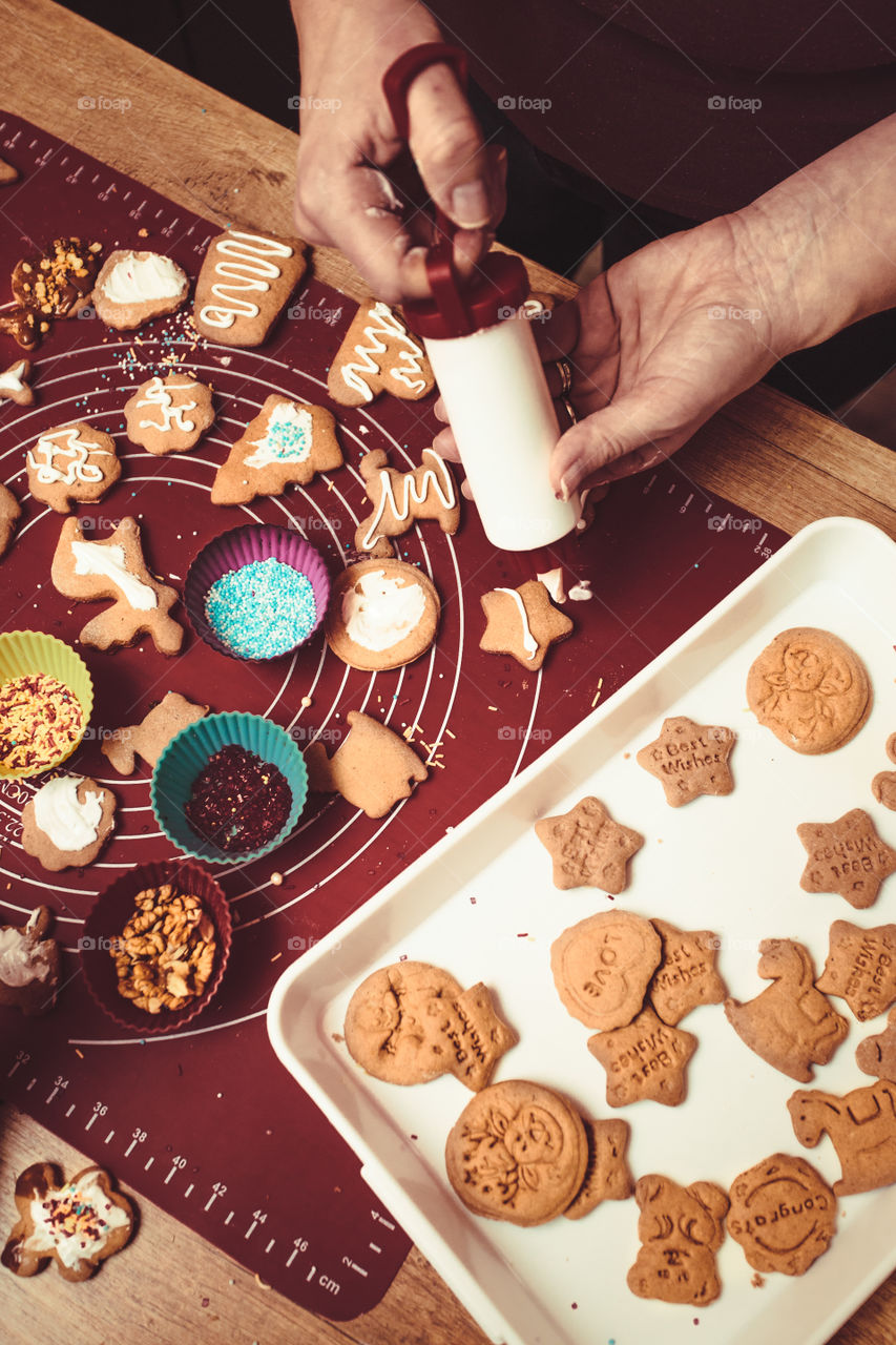 Baking Christmas cookies. Christmas gingerbread cookies in many shapes decorated with colorful frosting, sprinkle, icing, chocolate coating, toppers, put on table. Baking traditional cookies. Family celebrating Christmas. Baking at home
