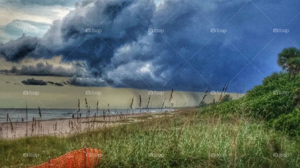 HDR shot of a quick moving rainstorm with heavy winds as it is approaching the beautiful and calm shores of the beach!