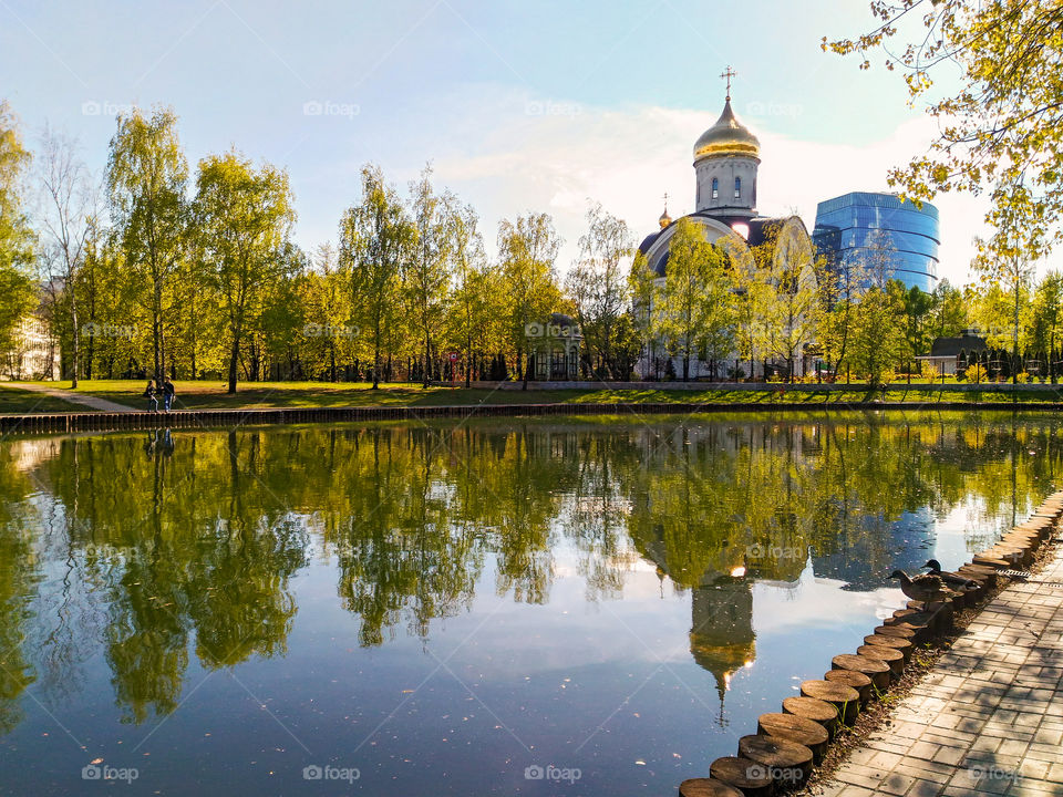 Spring landscape with a church and skyscrapers