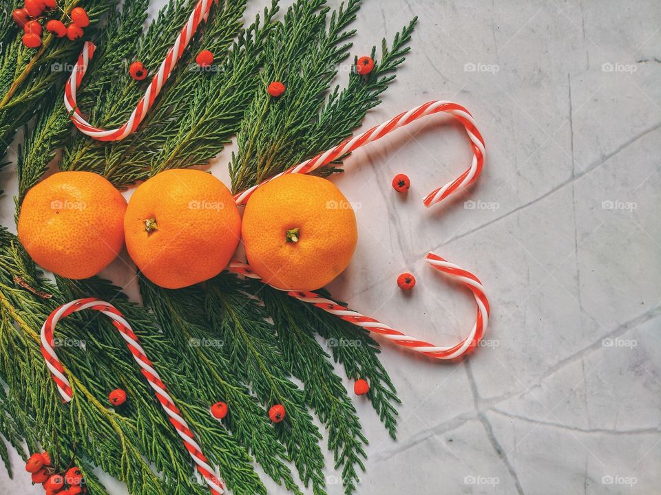 Christmas and New Year background with spruce branch, candies, decorations and tangerines Flat lay. Top view.