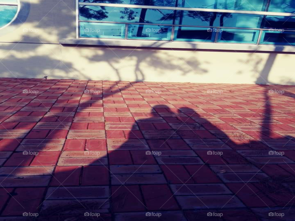 a shadow of a mother and child hugging each other while touching cheek by cheek.