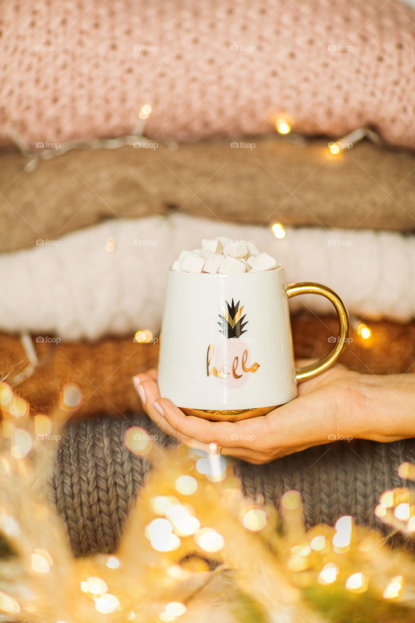 Female hand holding cup of coffee with marshmallow 