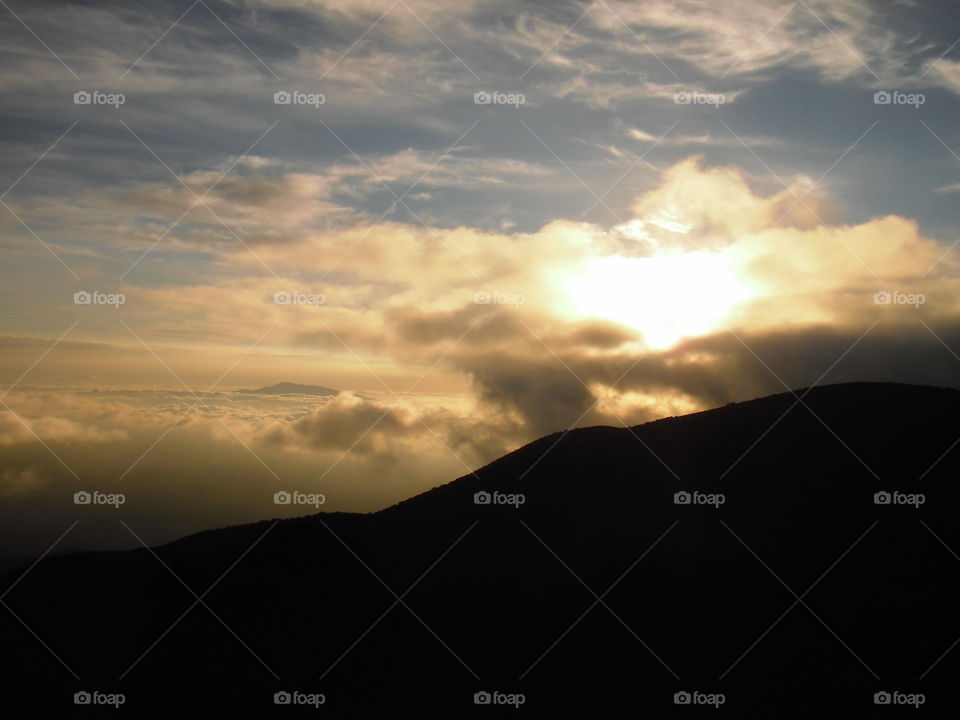 View of the sun setting into the clouds from Mauna Kea. 