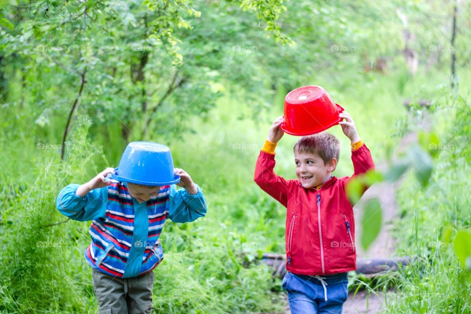 Children Playing in Rainy Spring Day with Buckets on Their Heads