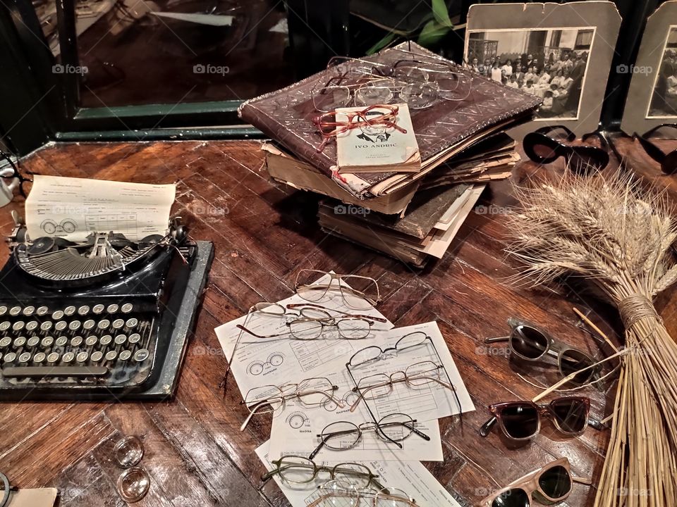 Glasses on the wooden table and typing machine with old photos