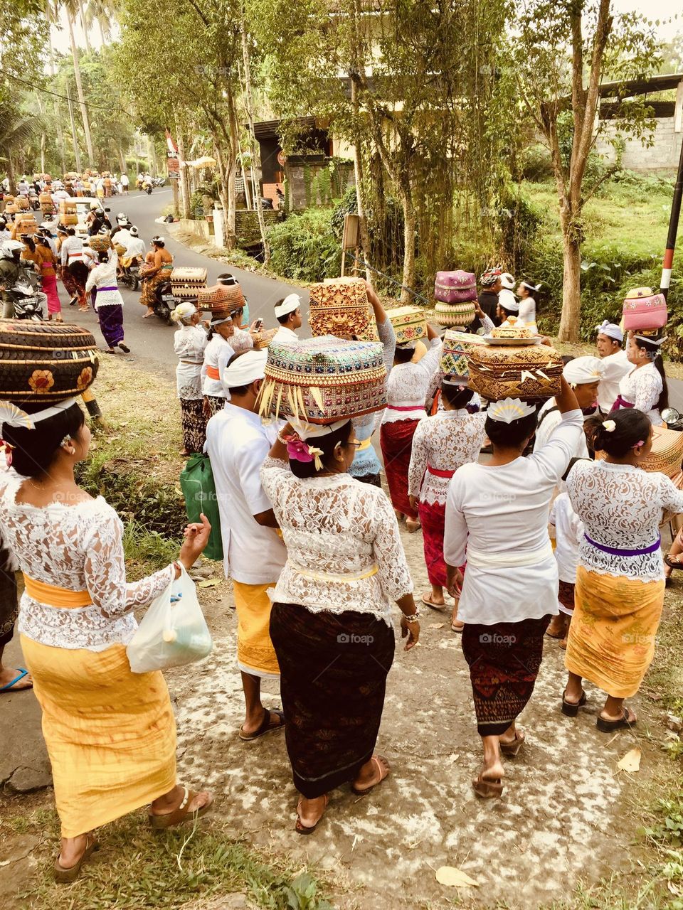 Balinese people of the island of Bali dressed with traditional clothes and transporting offers for the temple on their heads, ethnic group, native local people, indigenous people 