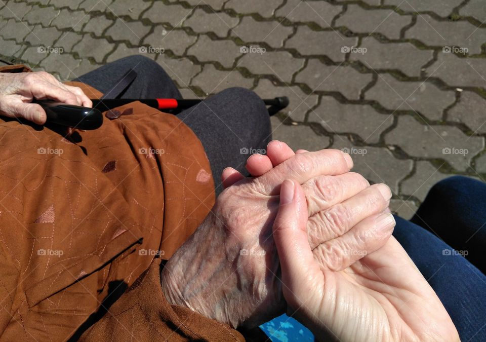 grandmother and granddaughter hands on the street pavement view