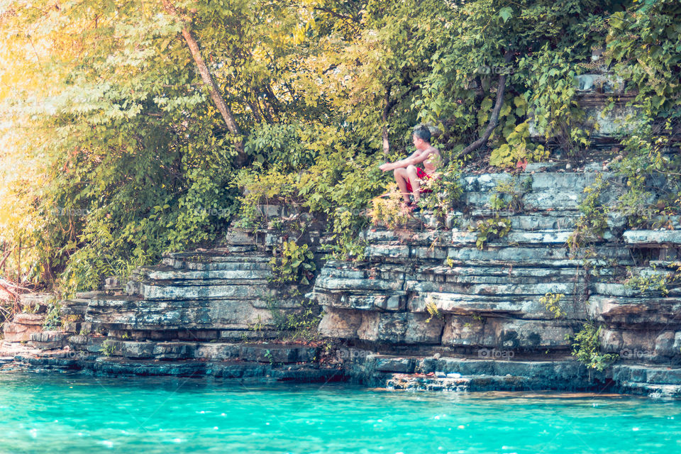 Boy on a Rock Wall at the Waters Edge