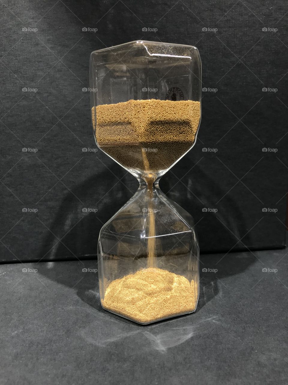 A clear, gold hourglass is flipped upside down and the sand starts running through.