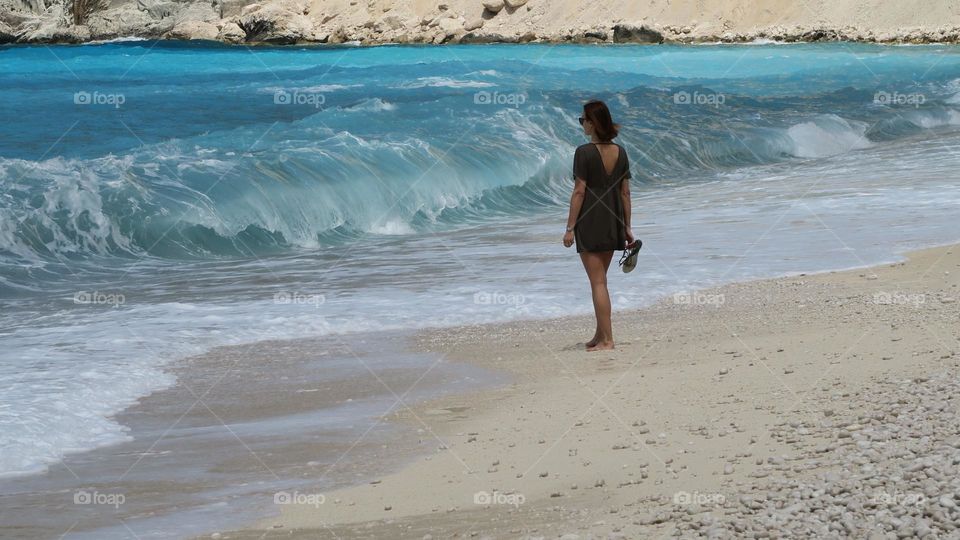 Woman and sea. Amazing waves. Blue sea. Beachfront. Sand and blue water.