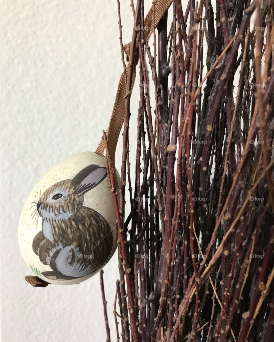 A Easter egg decoration hanging on a brown branch